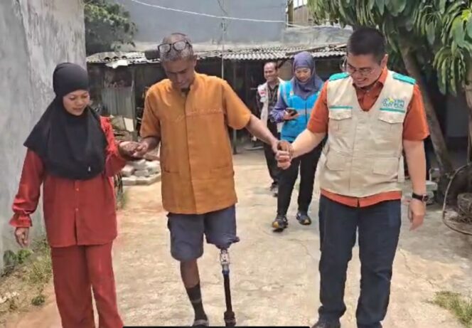 
					(kanan) Manager PLN Unit Pelaksana Pelayanan Pelanggan Pondok Kopi, Ari Tirtaprawita membantu (tengah) Ridwan H. Hilabi berjalan dengan kaki palsu yang diberikan.